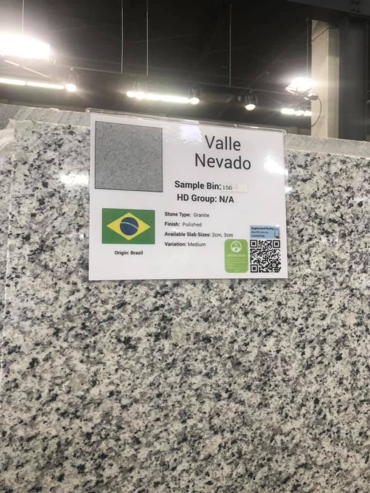 White sign on granite wall reading “Valle Nevado,” with a Brazilian flag and QR code.