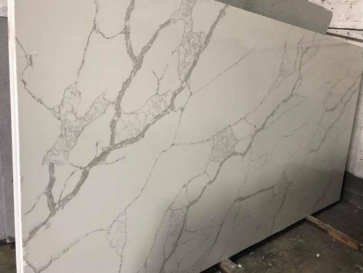 Large white marble-look tile slab with gray veining leaning against a wall in a workshop.