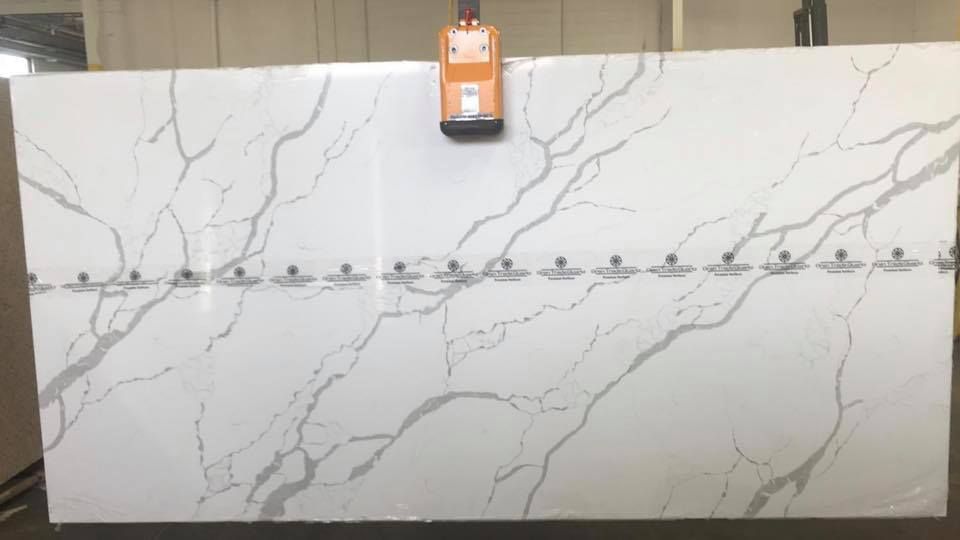 White marble-look panel with a horizontal row of small metal hooks and an orange device mounted at the top center.