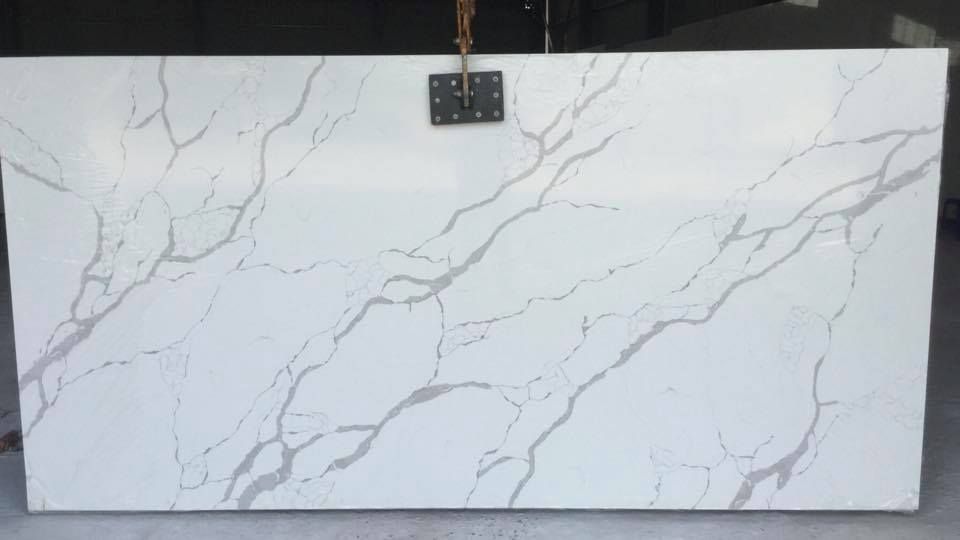 White marble-look slab with gray veining displayed against a wall, with a measuring label at the top.