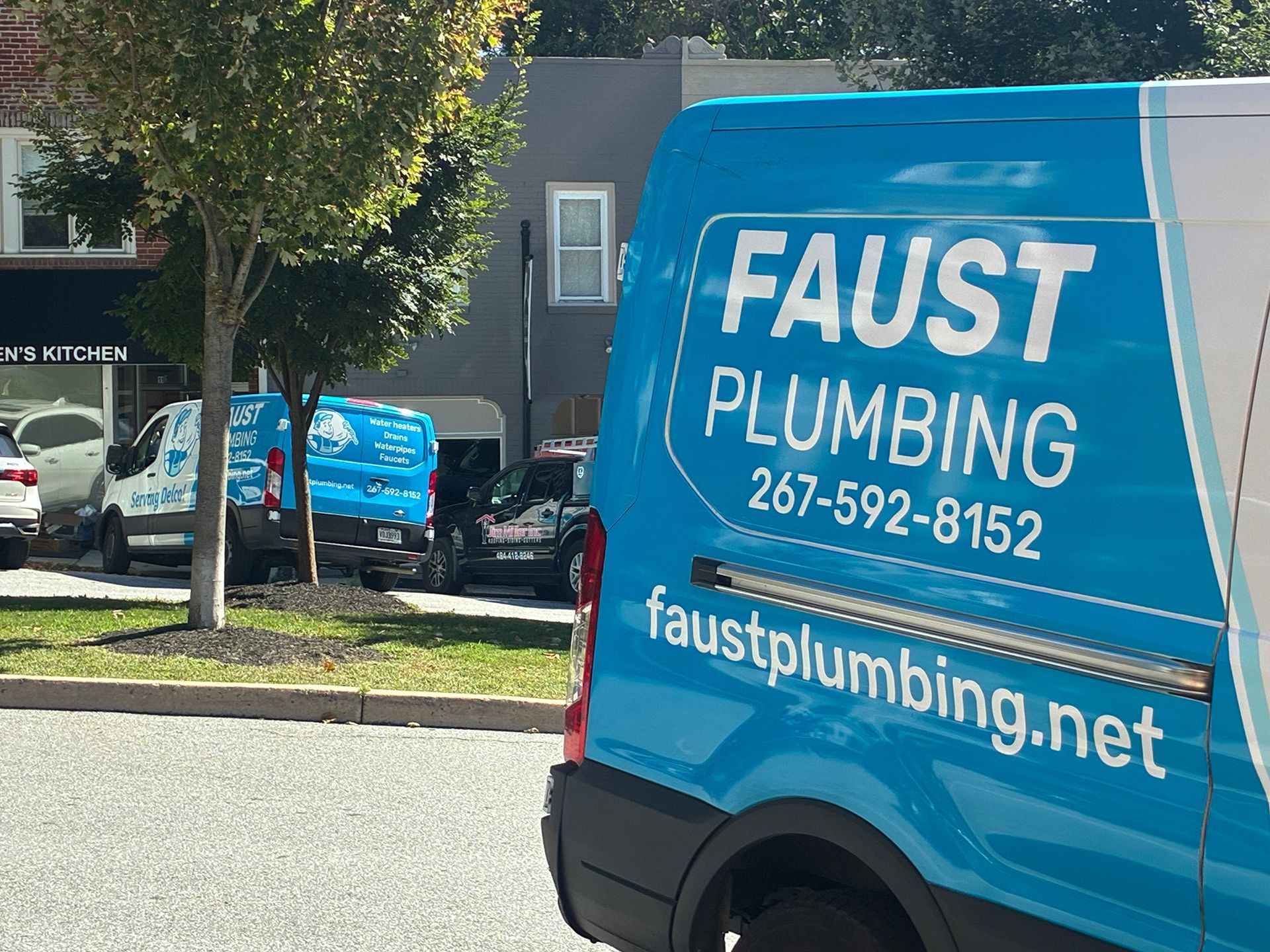 Blue Faust Plumbing van parked on a street, with logo and phone number visible.