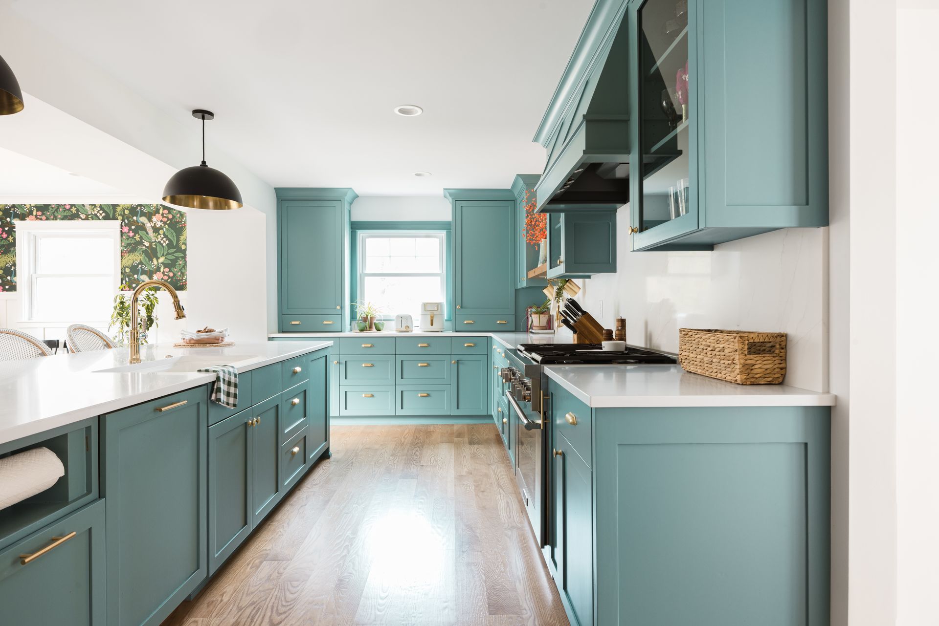 Bright teal kitchen with white countertops, island, and large window