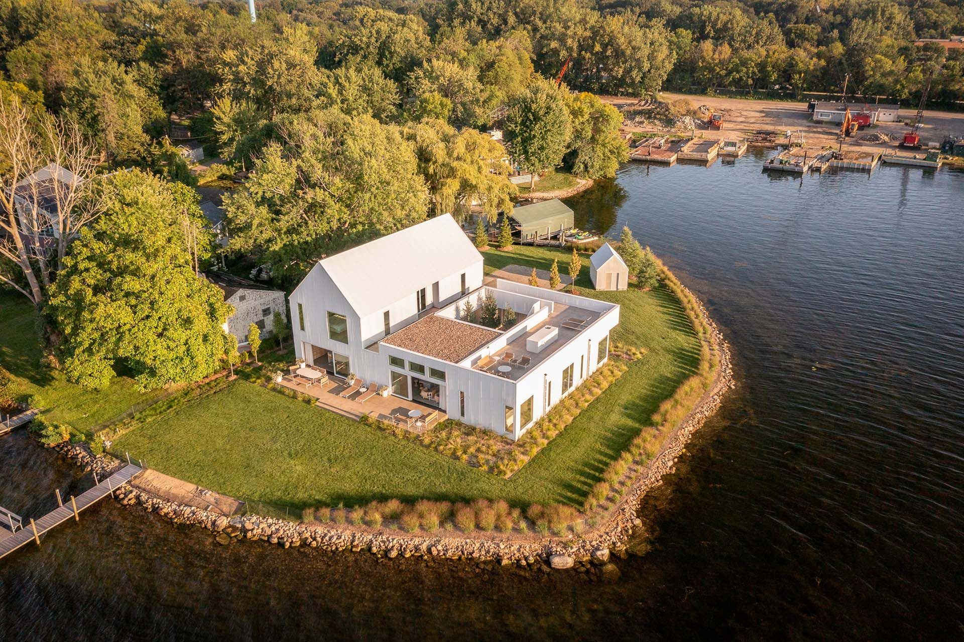 An aerial view of a white house on a lake.