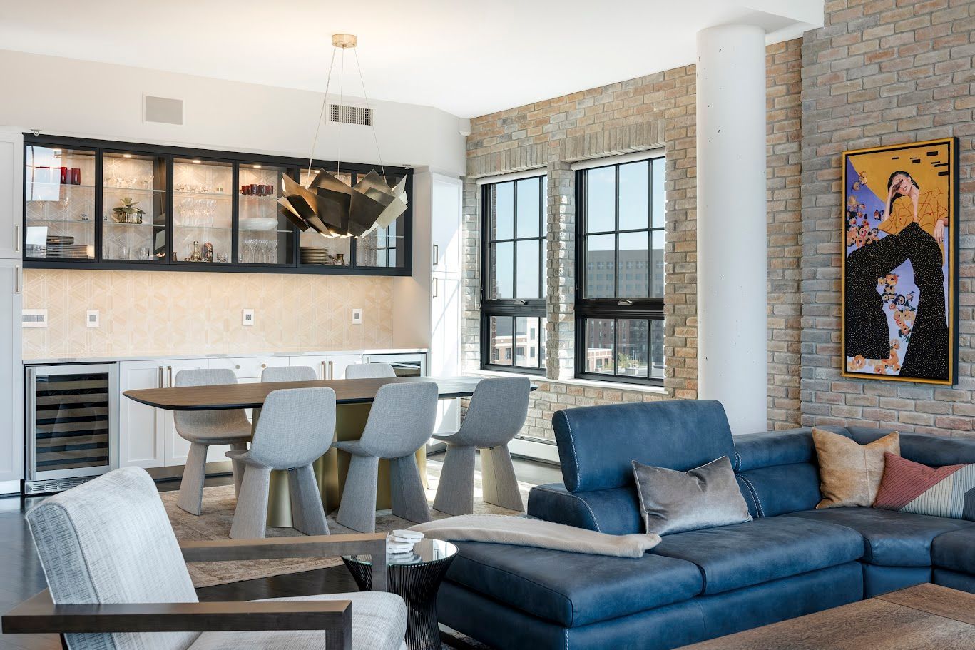 Modern living room with blue sectional, dining table, and stone accent wall.
