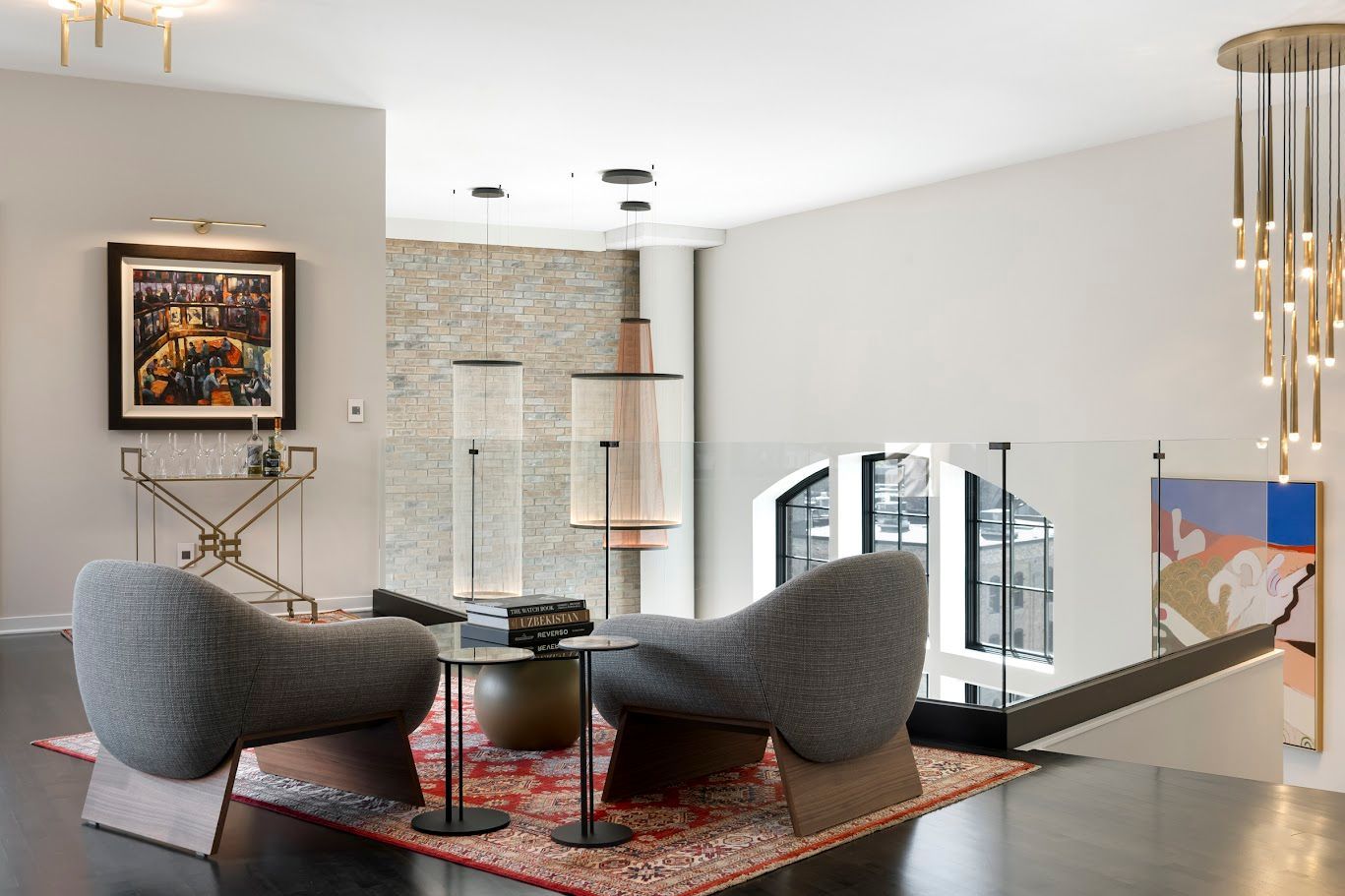 Modern living room with gray chairs, rug, and decorative lighting.