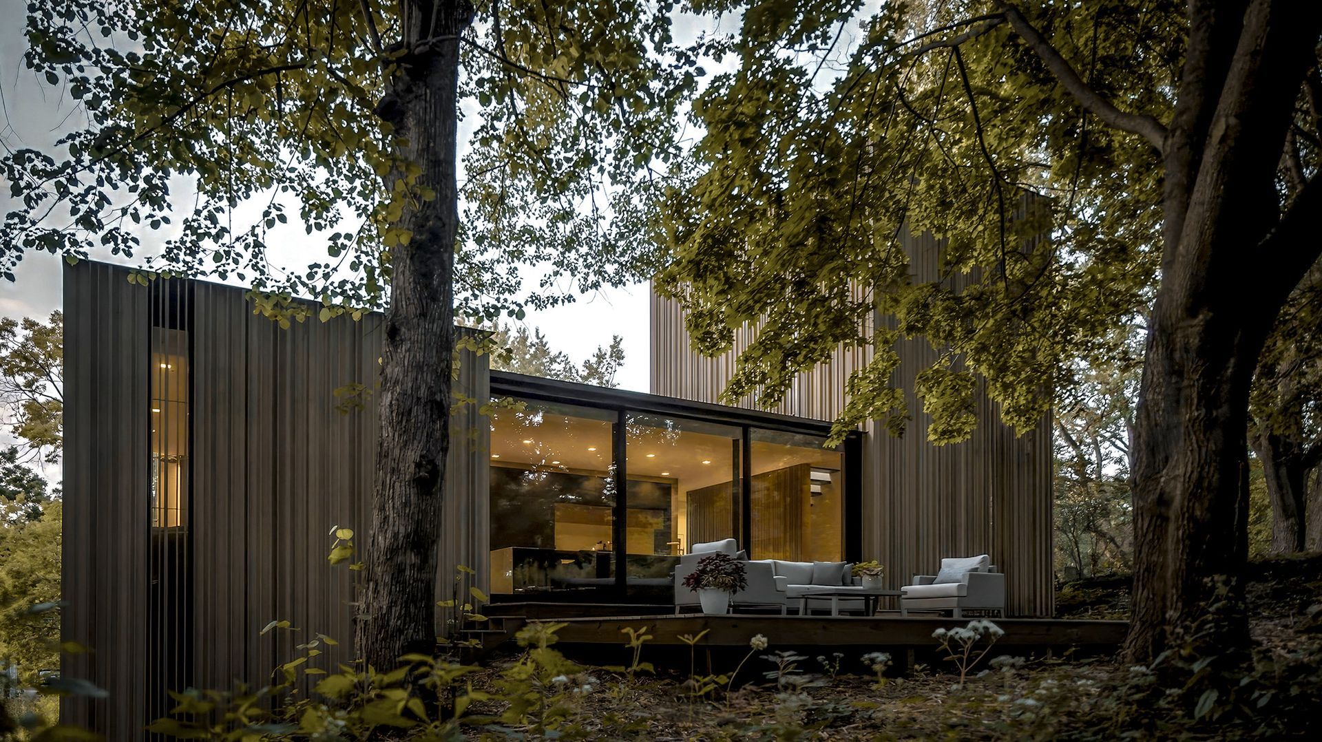 a modern wooden house in the middle of a forest surrounded by trees