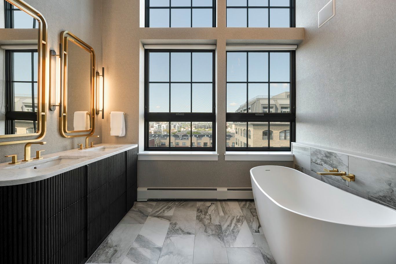 Luxurious bathroom with black vanity, gold fixtures, large windows, and a soaking tub.