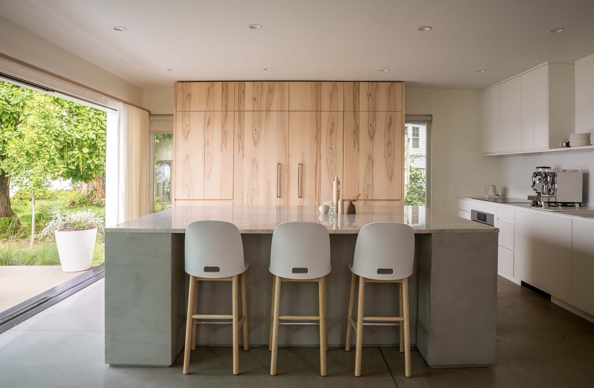 A kitchen with a large island and three stools.