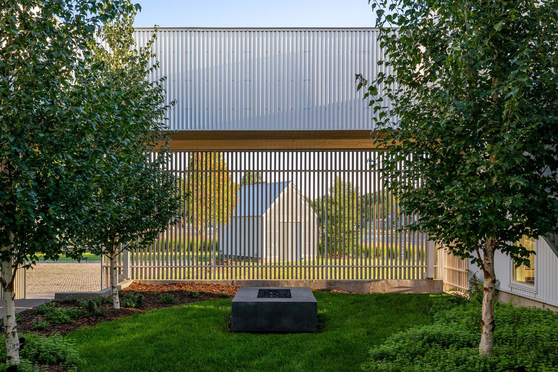 There is a fire pit in the middle of the grass in front of a building.