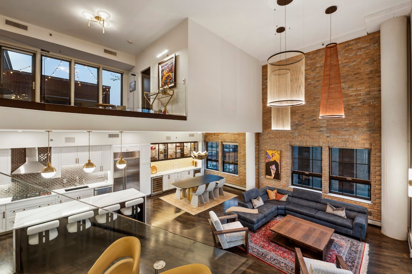 Spacious loft with kitchen, dining area, and living room; exposed brick wall and mezzanine.