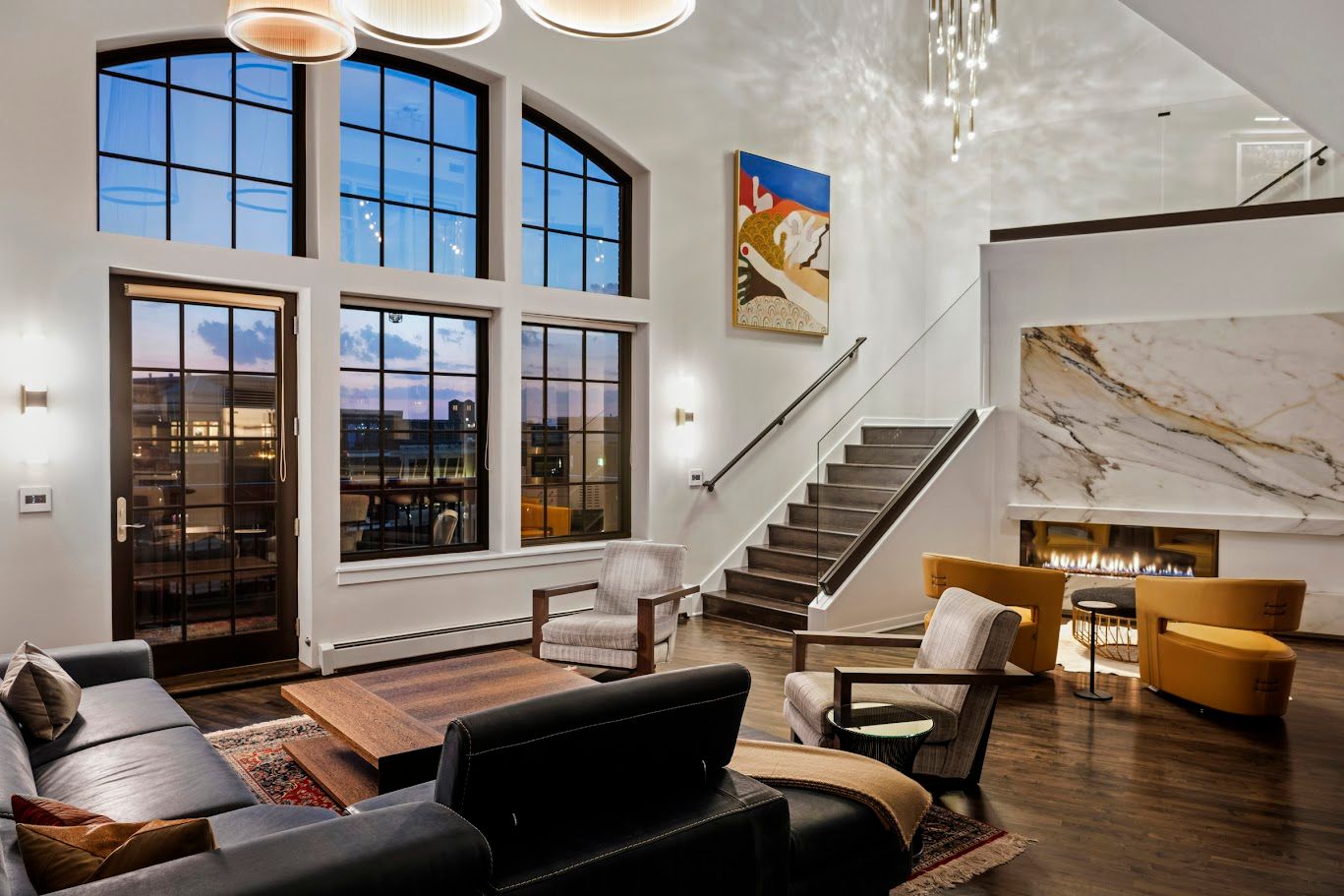 Living room with large windows, staircase, fireplace, and modern furniture.