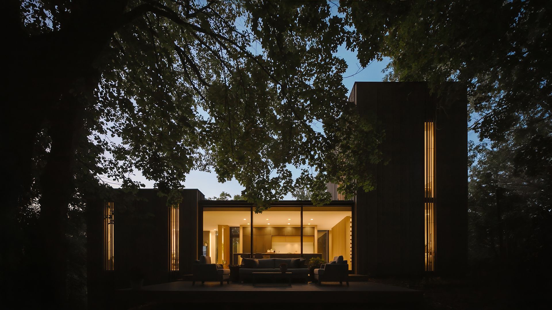 a house is lit up at night with trees in the background