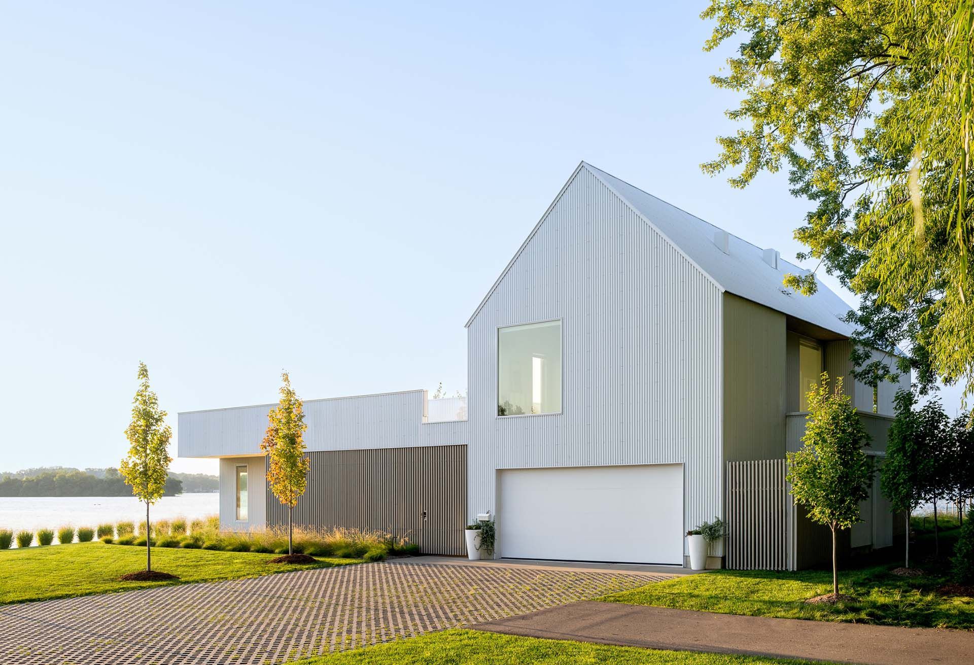 A white house with a sharply pitched roof and a white garage door.
