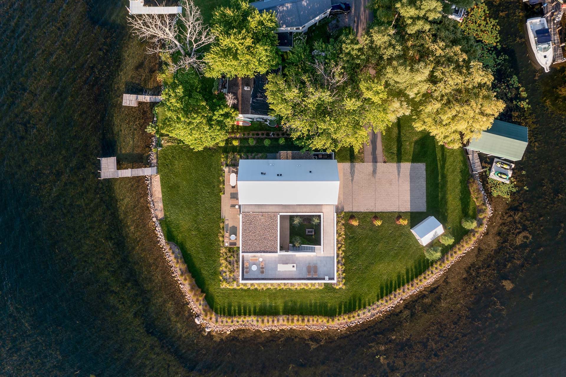 An aerial view of a house on a small island in the middle of a body of water