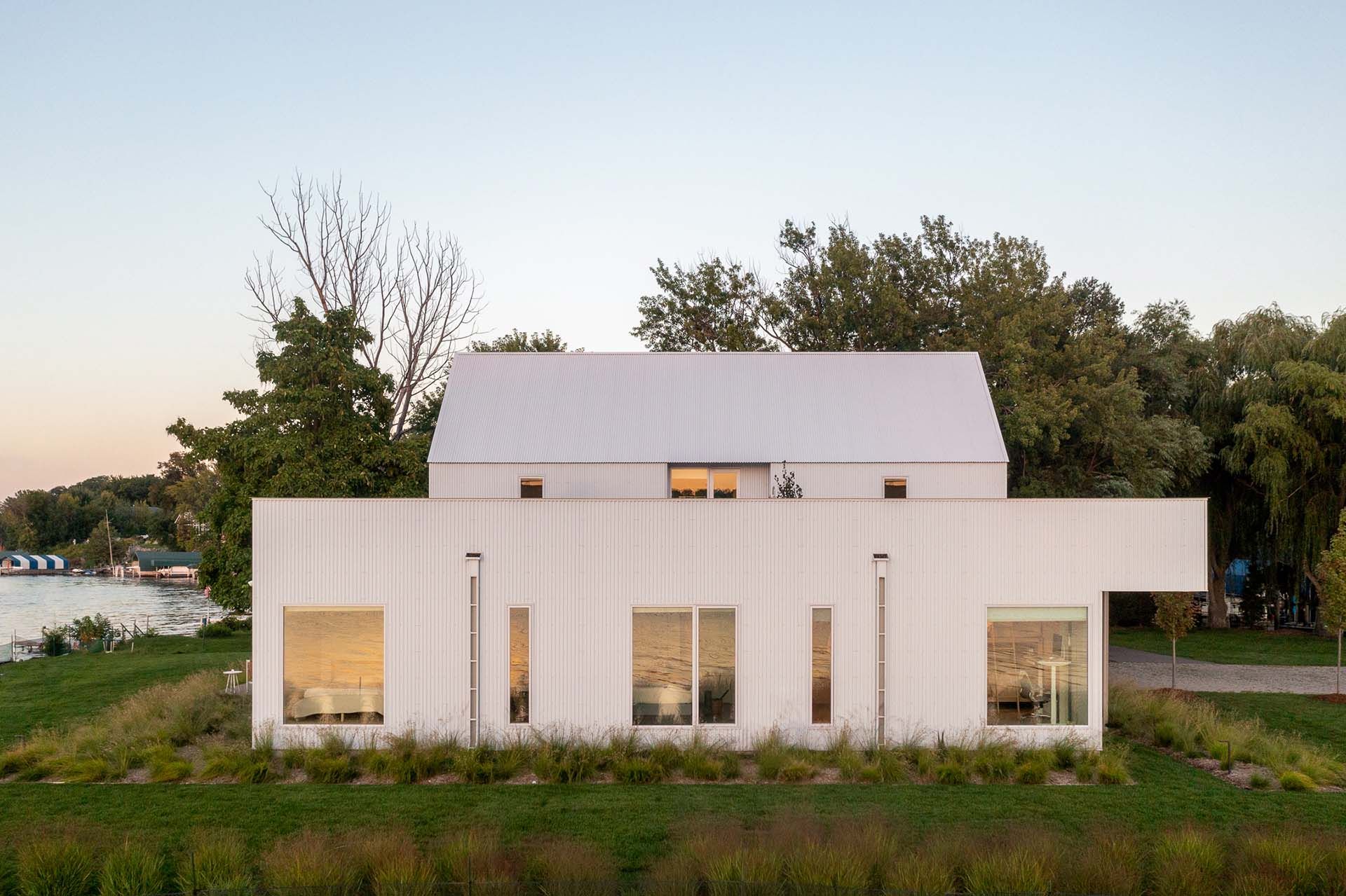 A white house with a white roof is sitting next to a body of water.