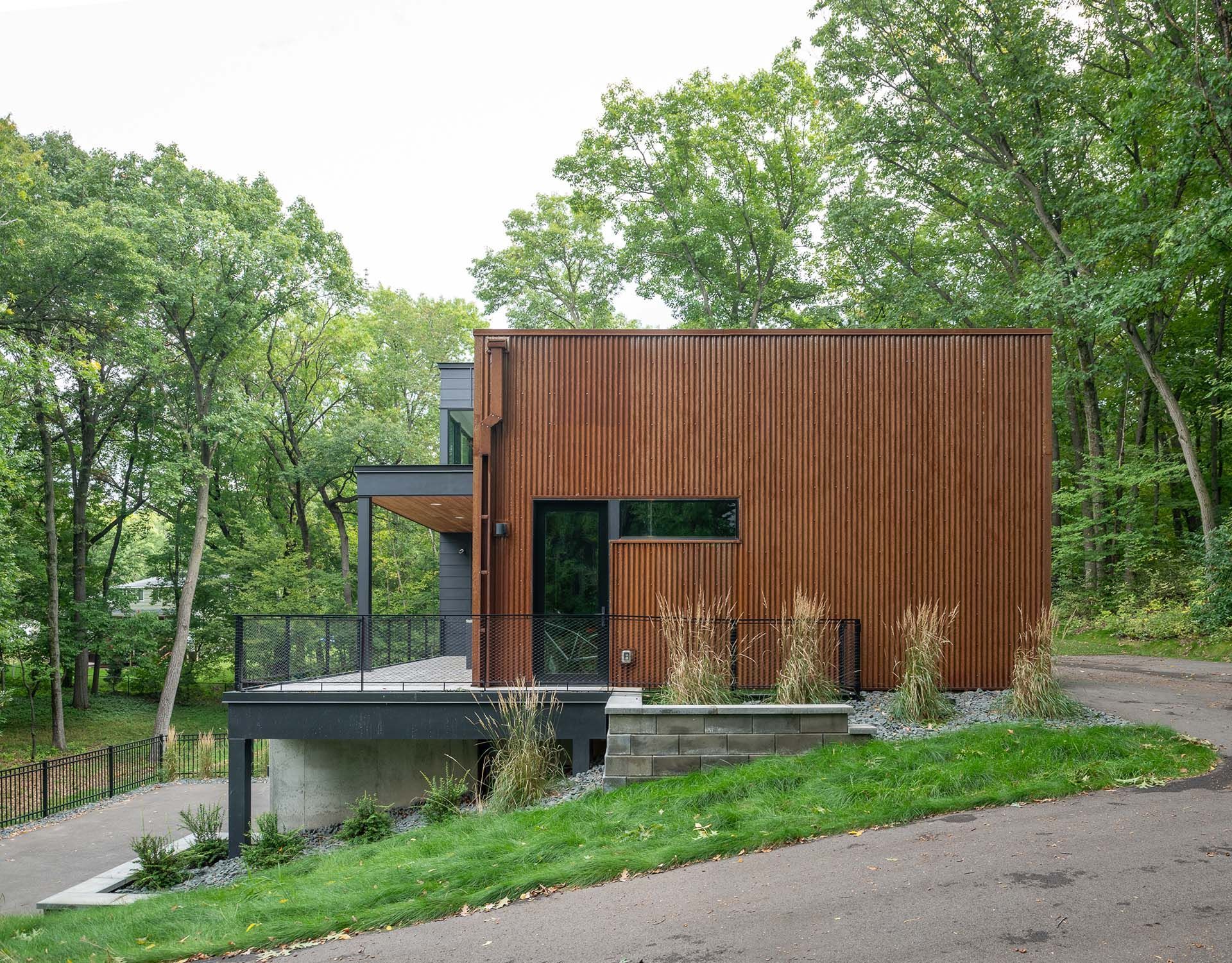 A small house is sitting on top of a lush green hill surrounded by trees.