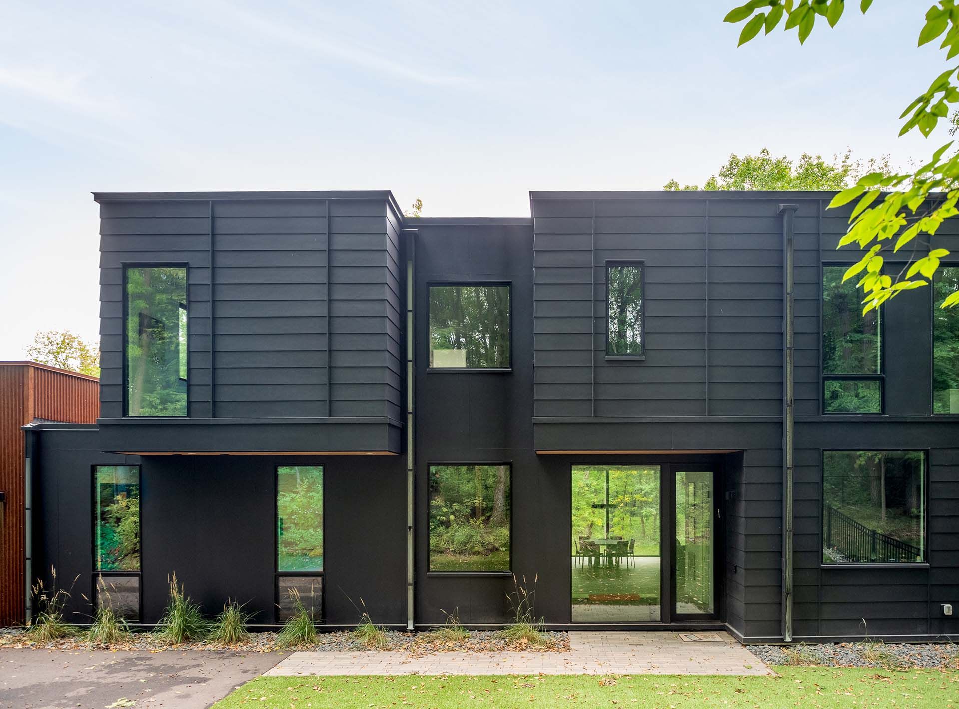 The front of a black house with a lot of windows.