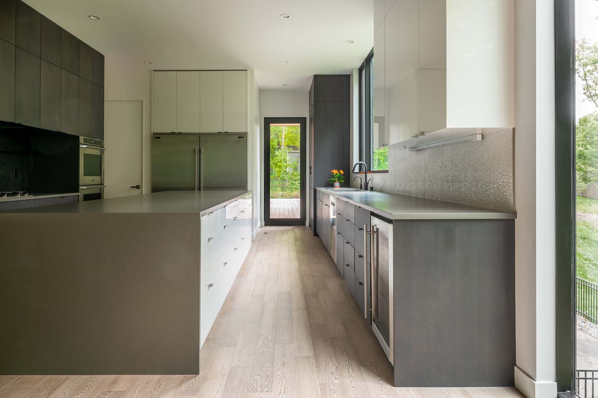 It is a long kitchen with a lot of cabinets and a large island.