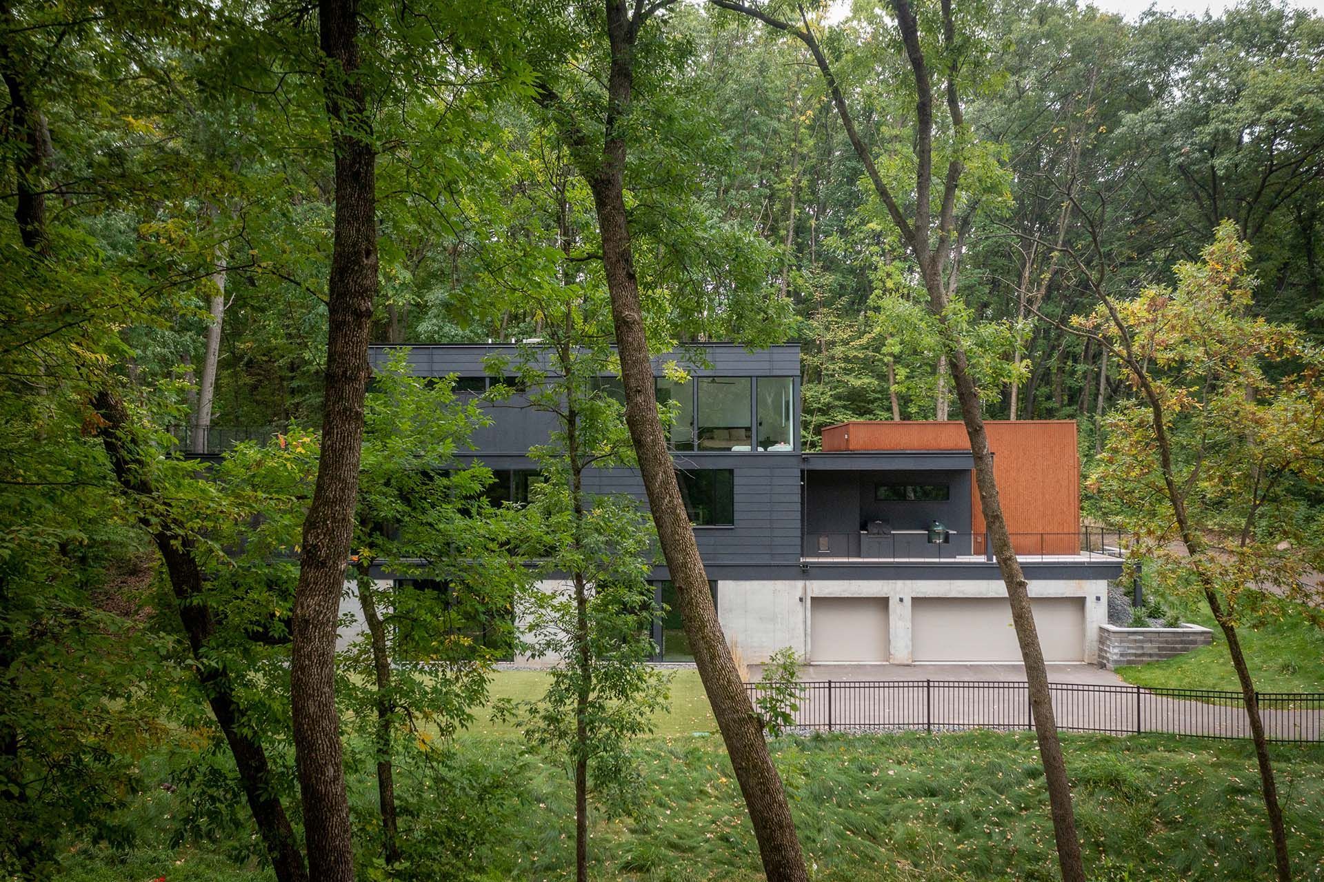 A modern house is surrounded by trees in the middle of a forest.