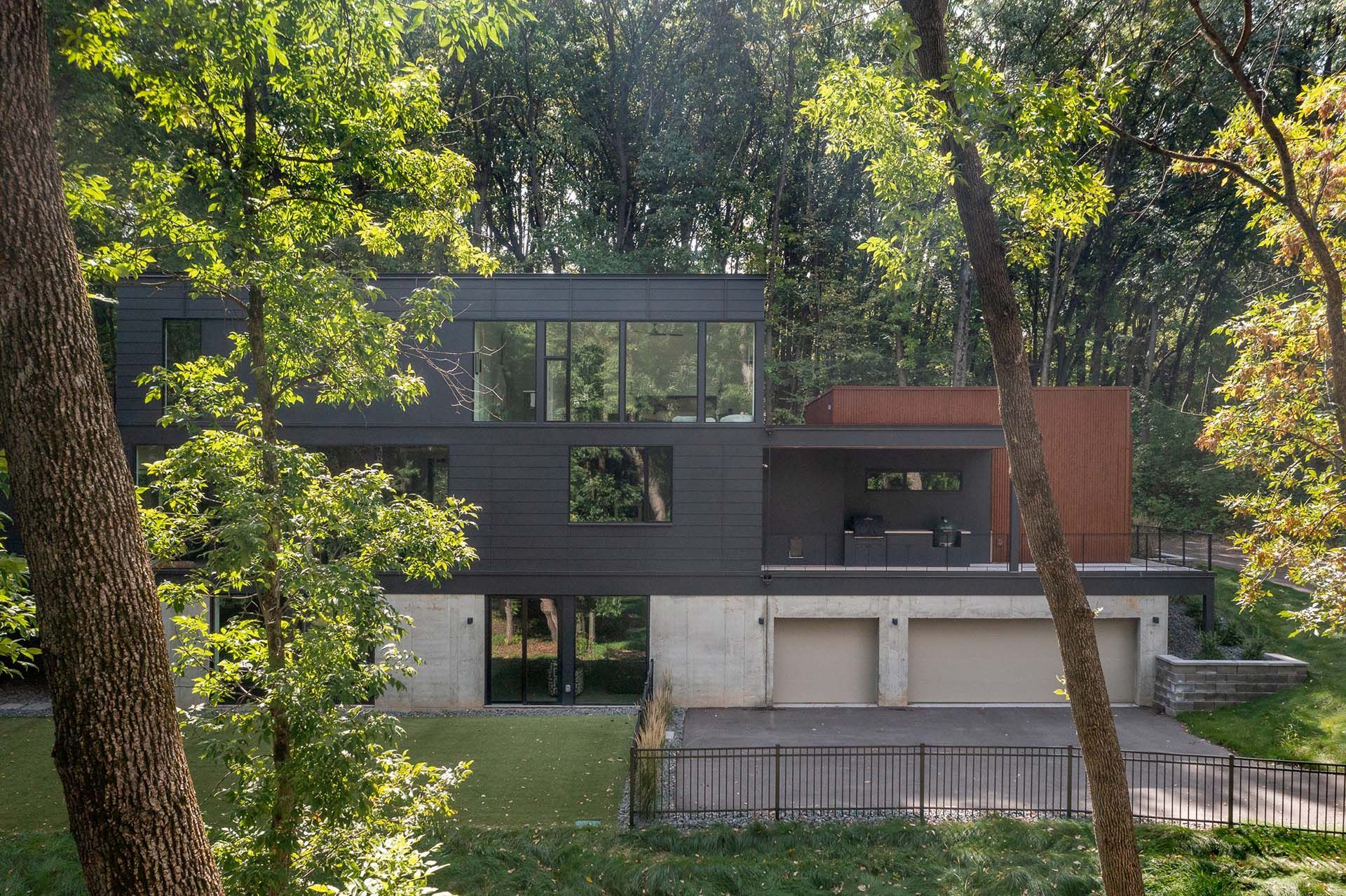 A modern house is surrounded by trees in the middle of a forest.