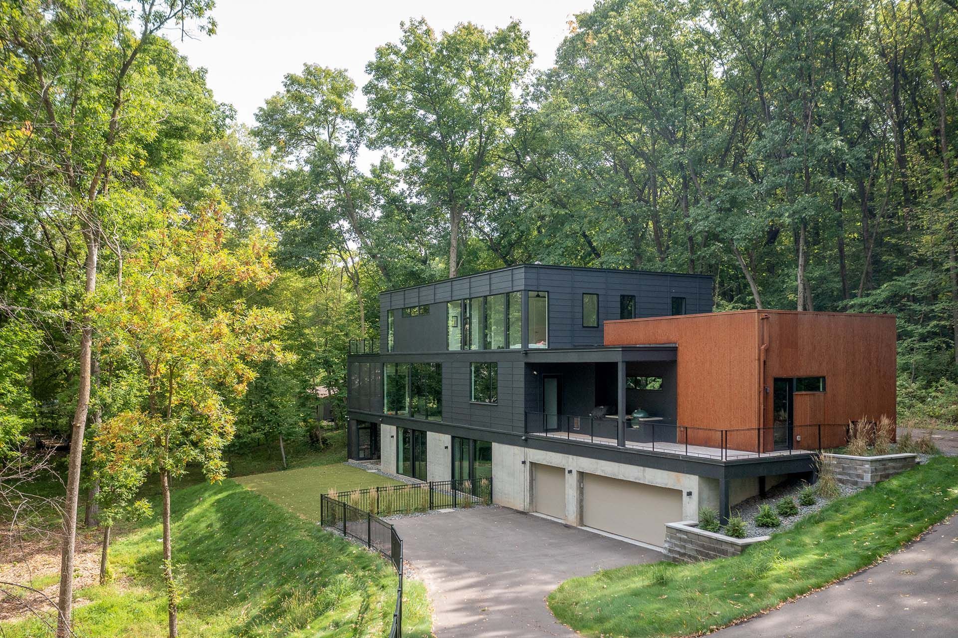 A large house is sitting on top of a hill in the middle of a forest.