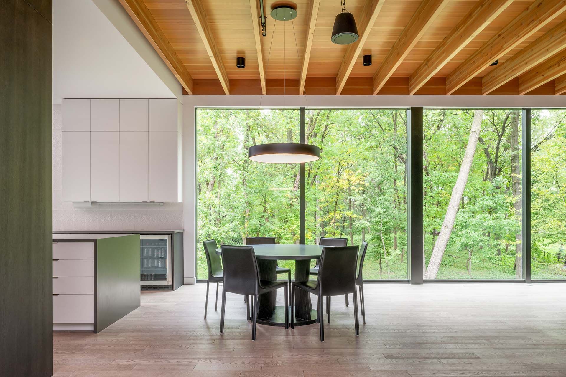 A dining room with a table and chairs in front of a large window.