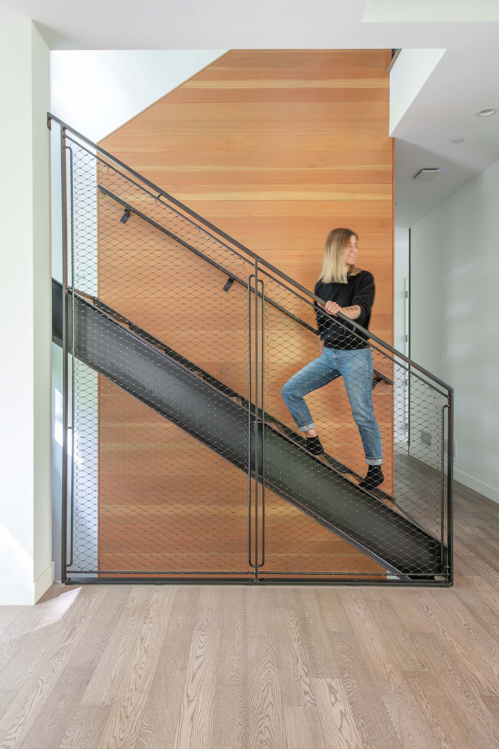 A woman is walking up a set of stairs in a house.