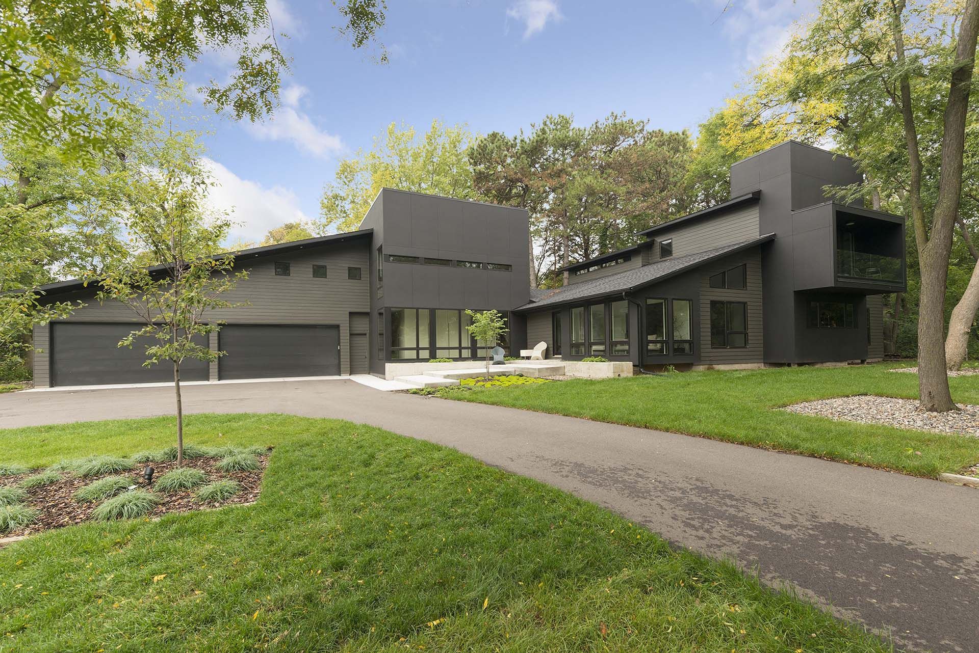 A large black house with a driveway leading to it