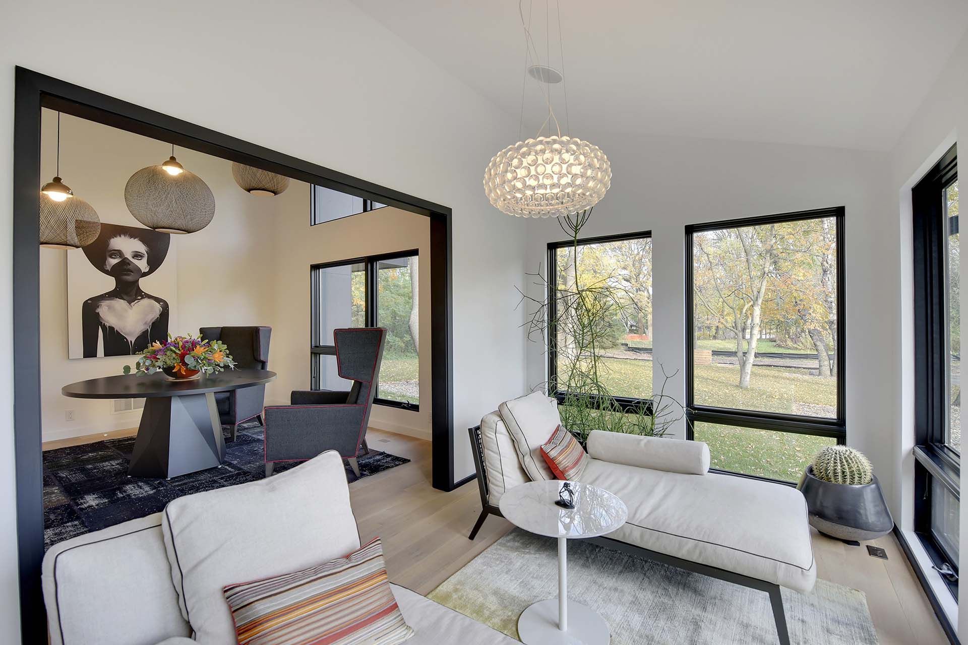 A living room with a chaise lounge , couch , table and windows.