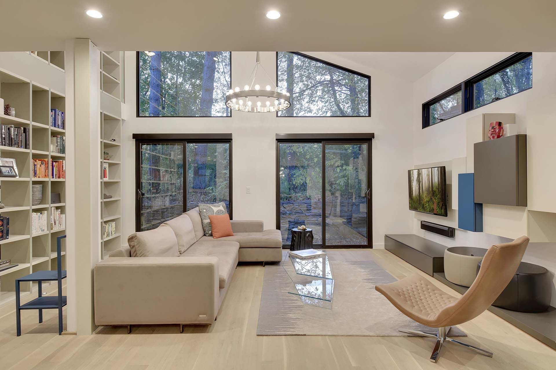 A living room with a couch , chair , bookshelf and television.