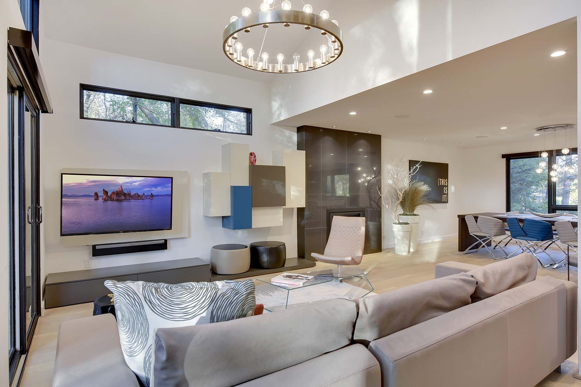 A living room with a couch , chair , television and chandelier.