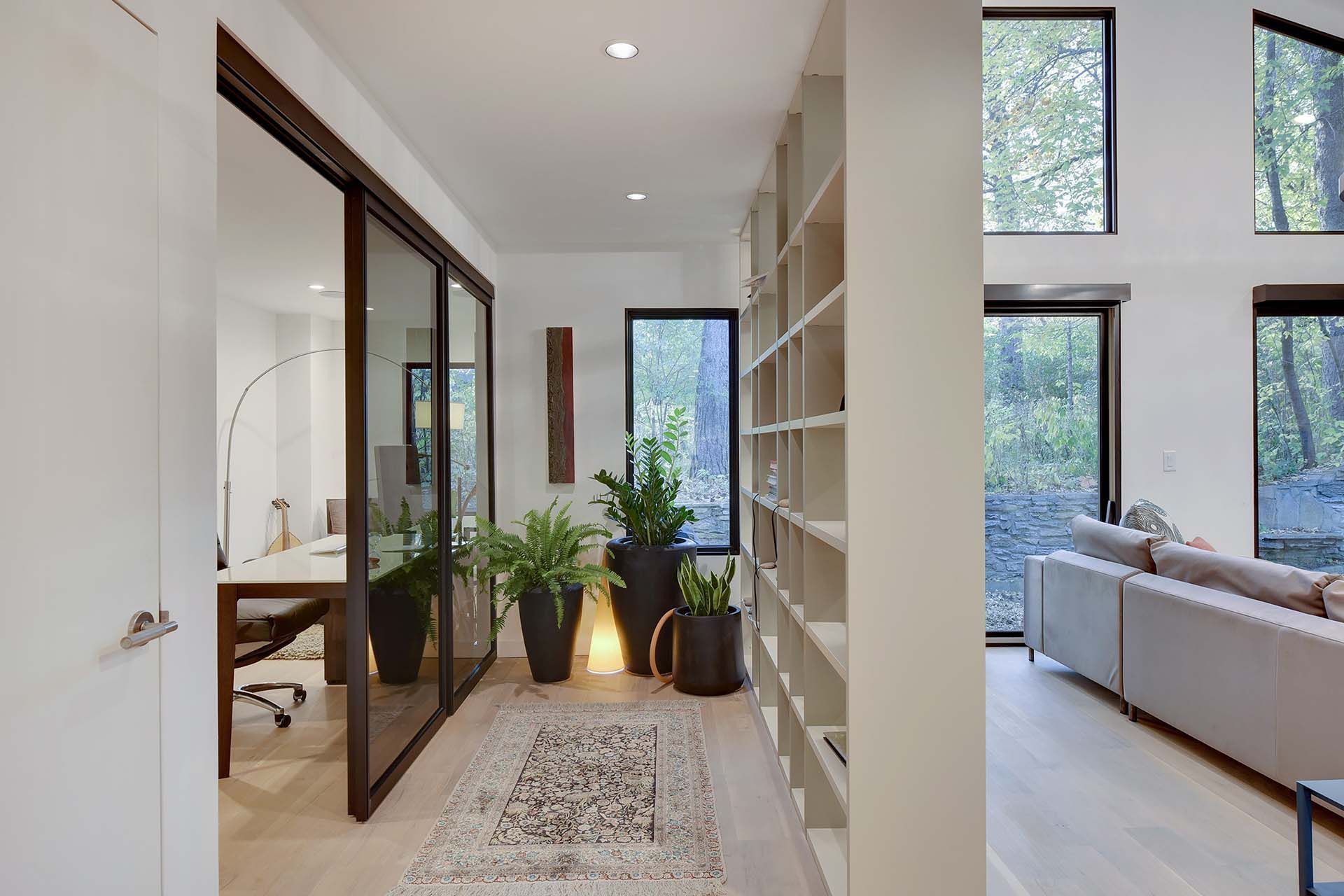 A hallway leading to a living room with a couch and a desk.