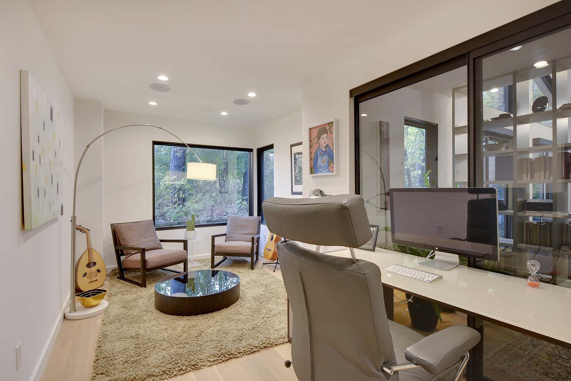 A living room with a desk and chairs and a computer on it
