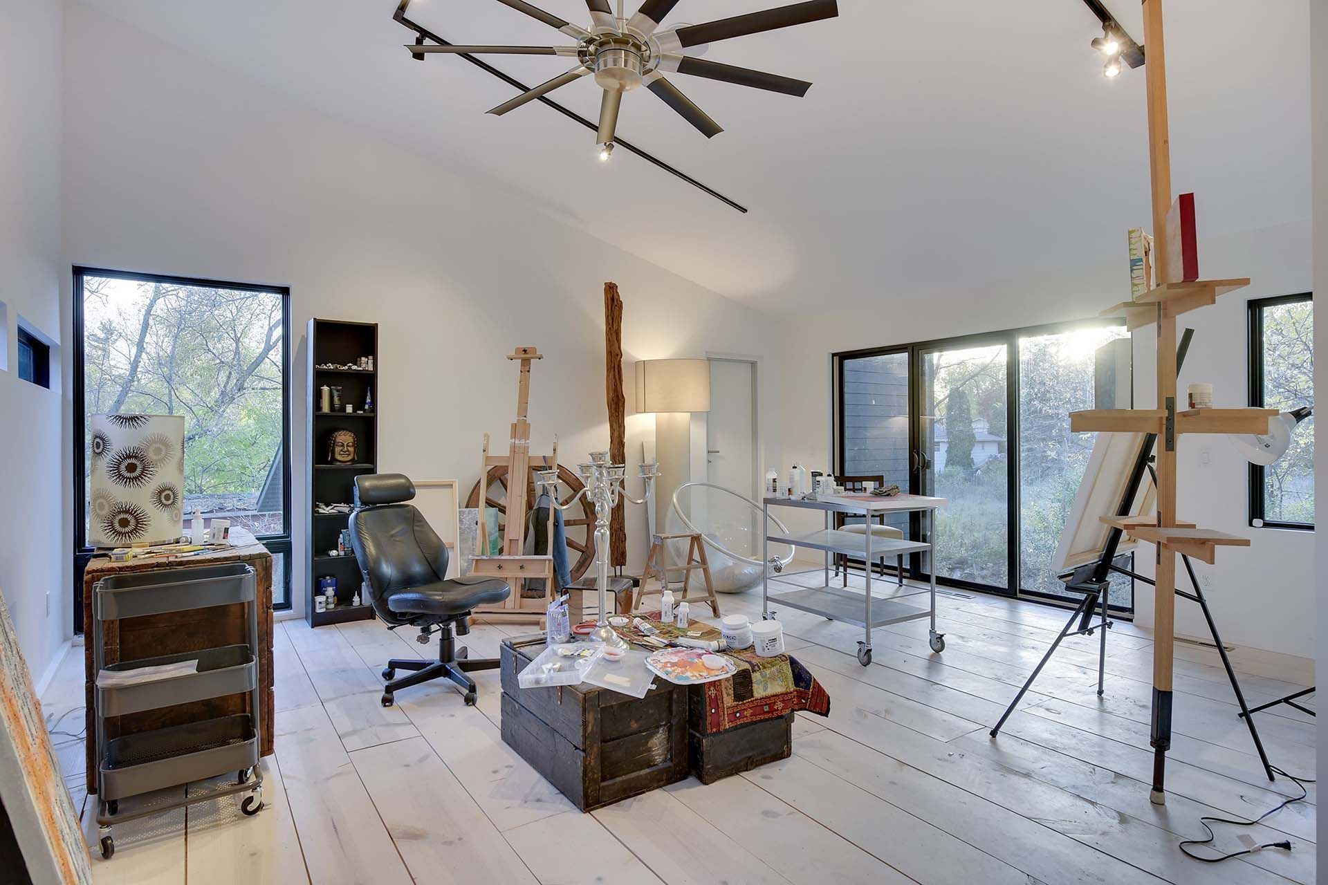 An artist 's studio with a ceiling fan and a chair