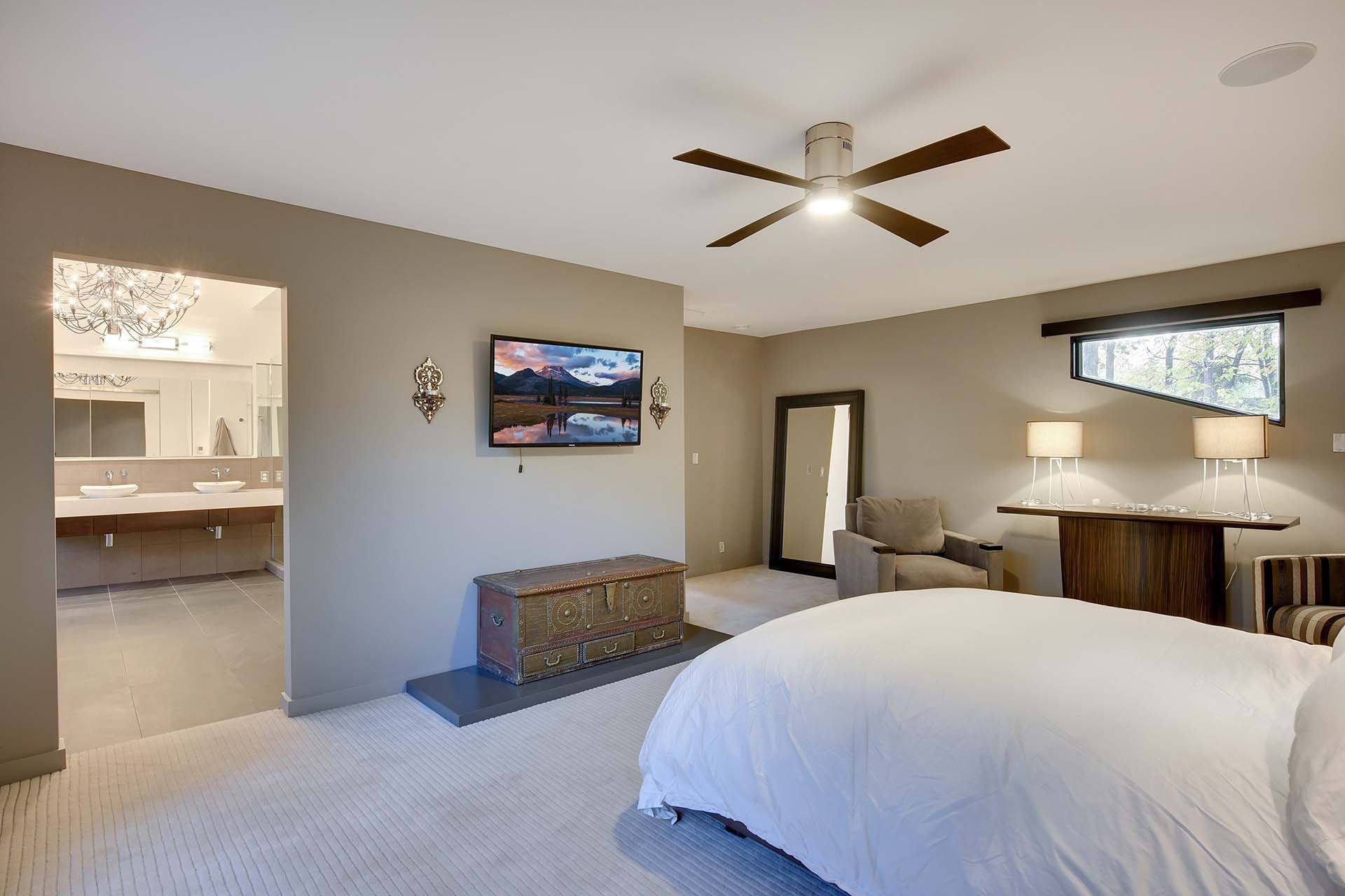 A bedroom with a large bed and a flat screen tv on the wall.