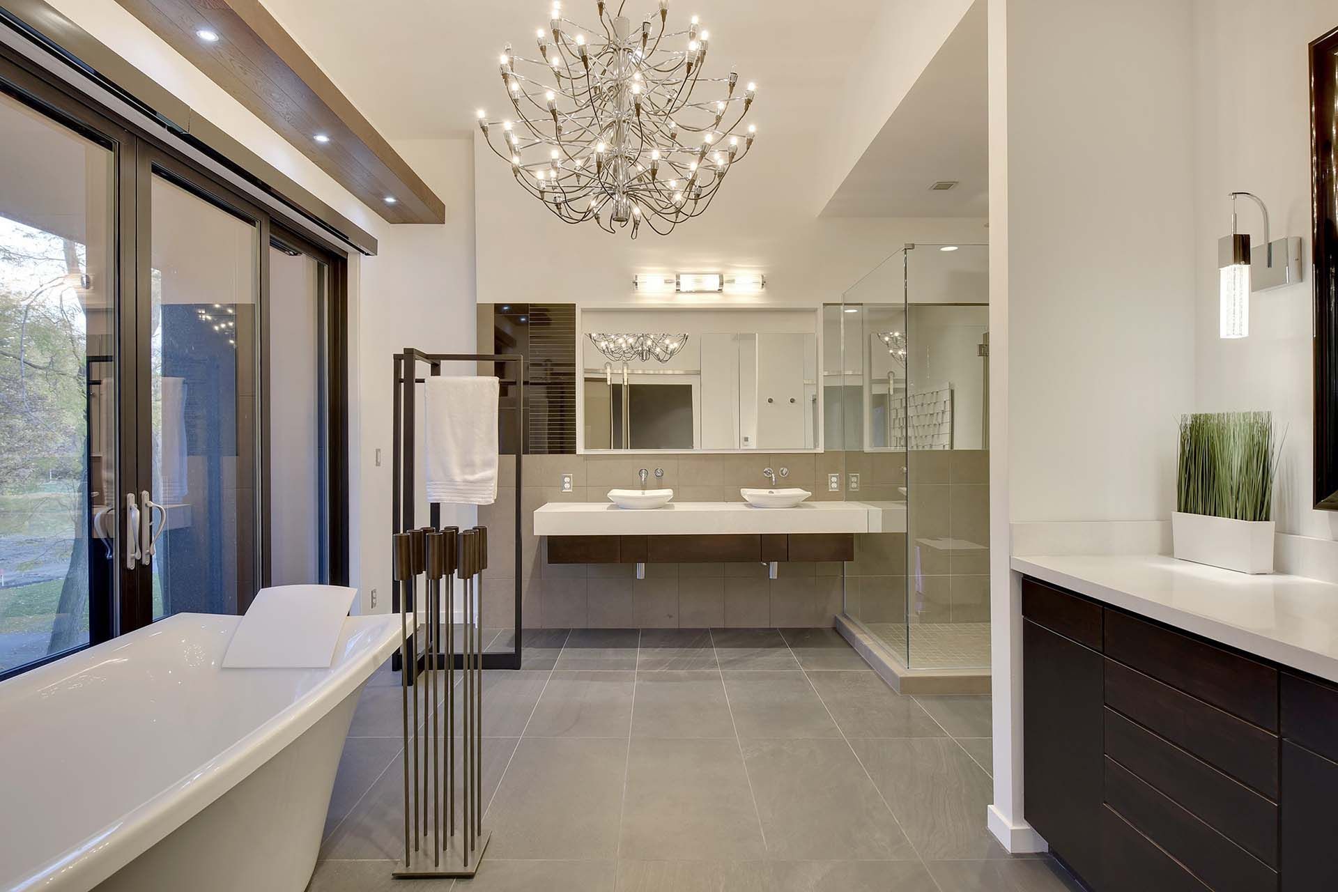 A bathroom with two sinks , a bathtub and a chandelier hanging from the ceiling.