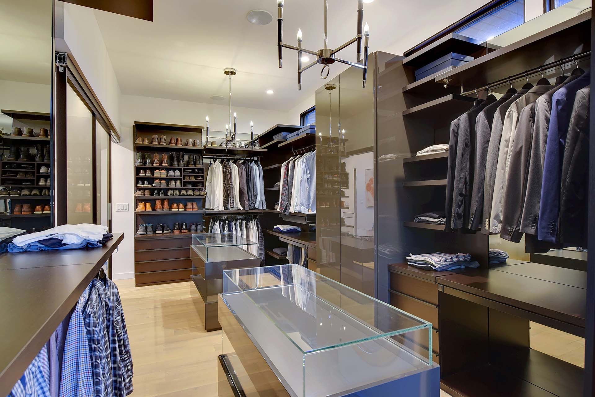 A walk in closet filled with lots of clothes and a glass display case.