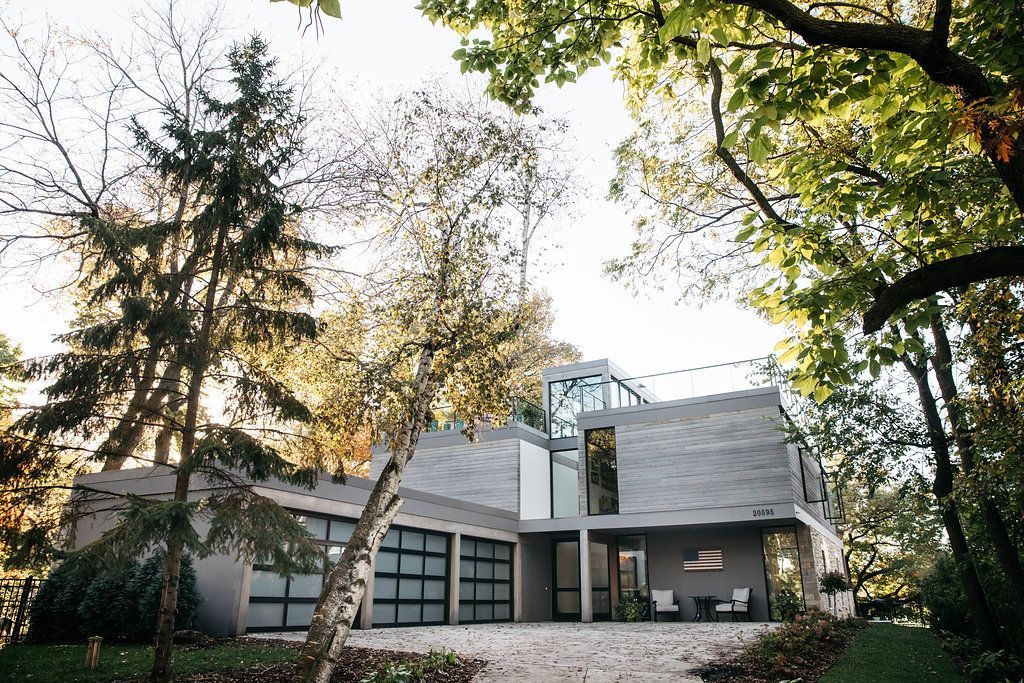 A large house is surrounded by trees and a gravel driveway