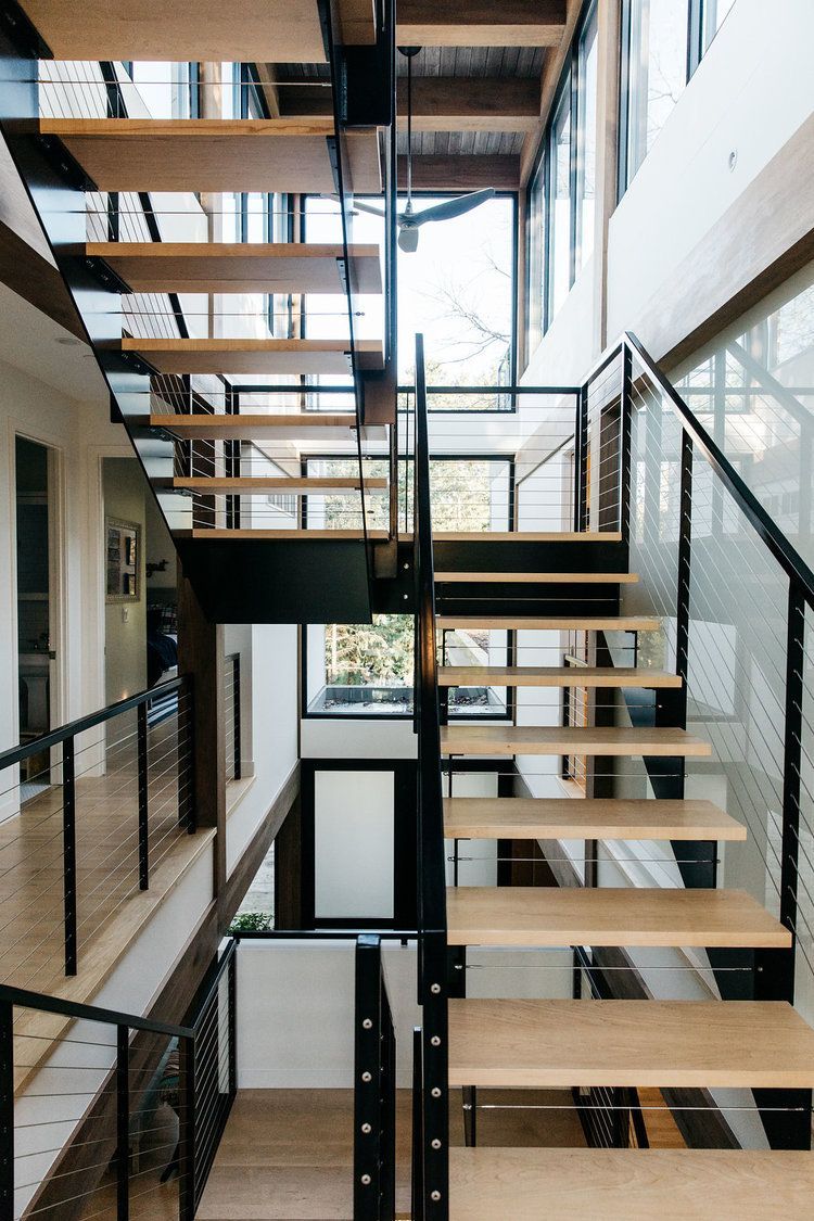 A modern staircase with wooden steps and a black railing in a house.