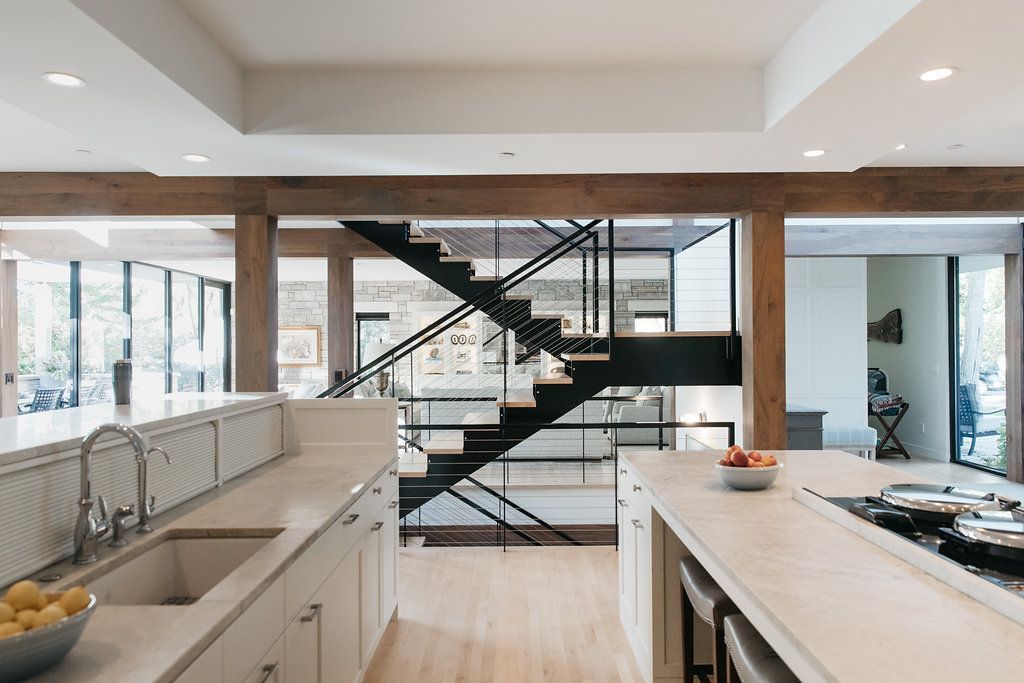 A kitchen with a sink , stove , and stairs leading to the second floor.