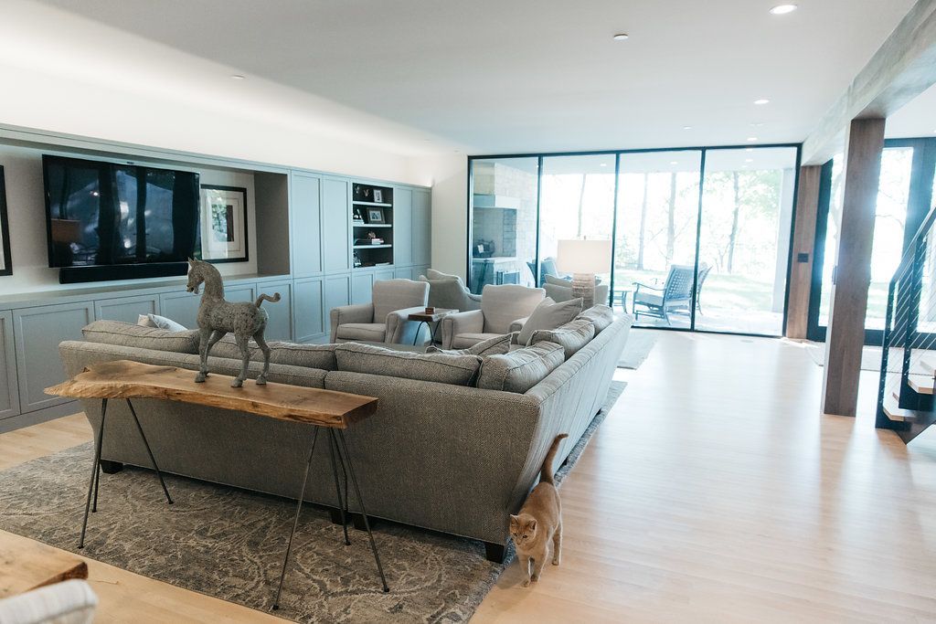 A living room with a couch , chairs , a table and a dog.