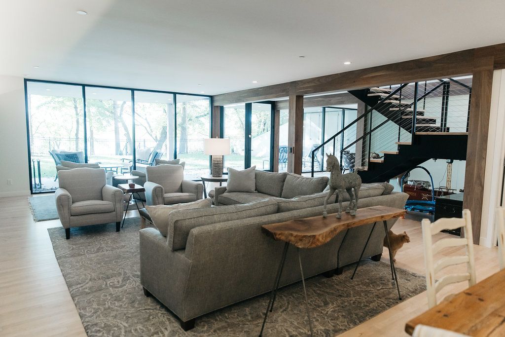 A living room with a couch , chairs , table and stairs.