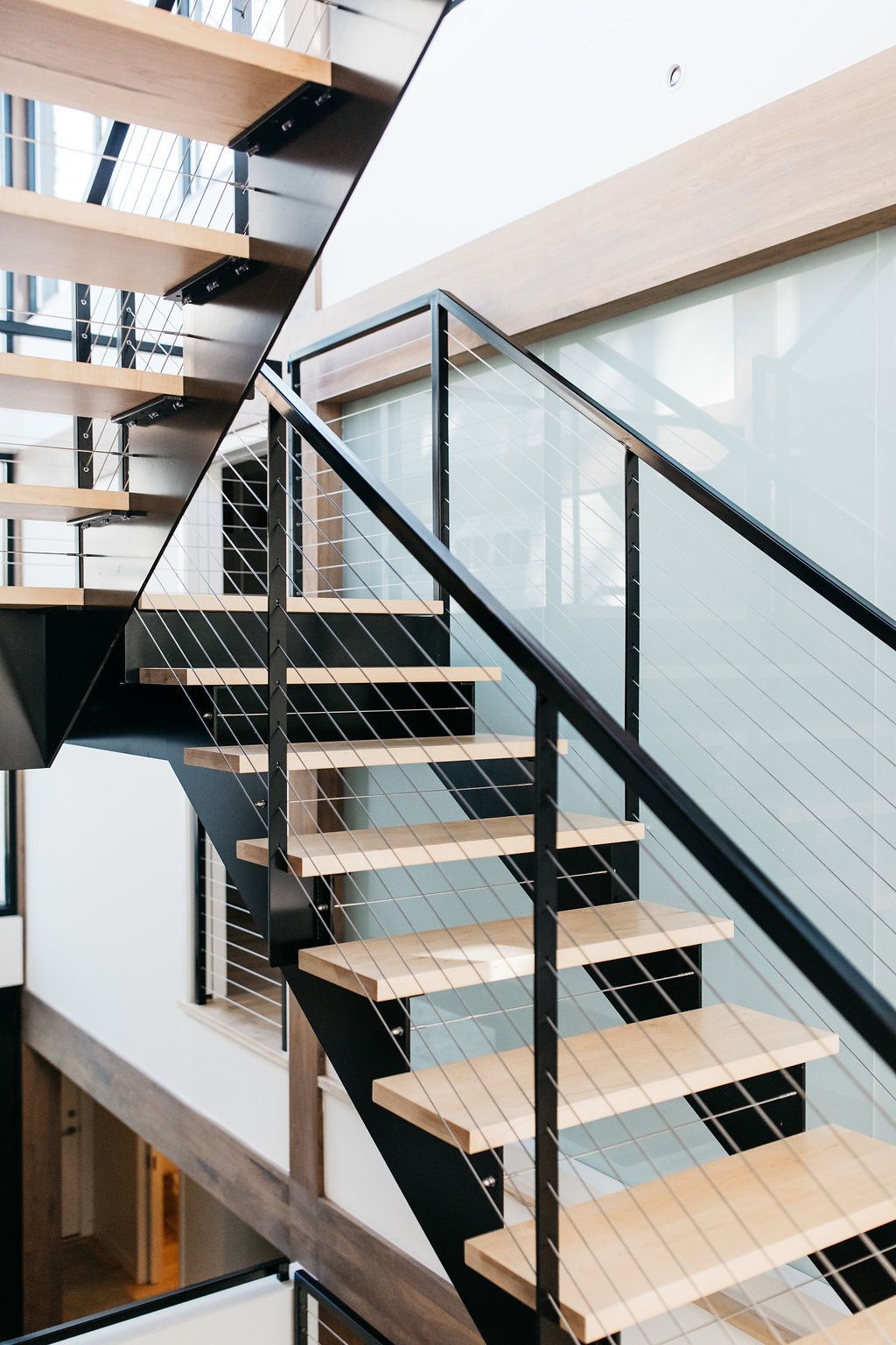 A modern staircase with wooden steps and a glass railing