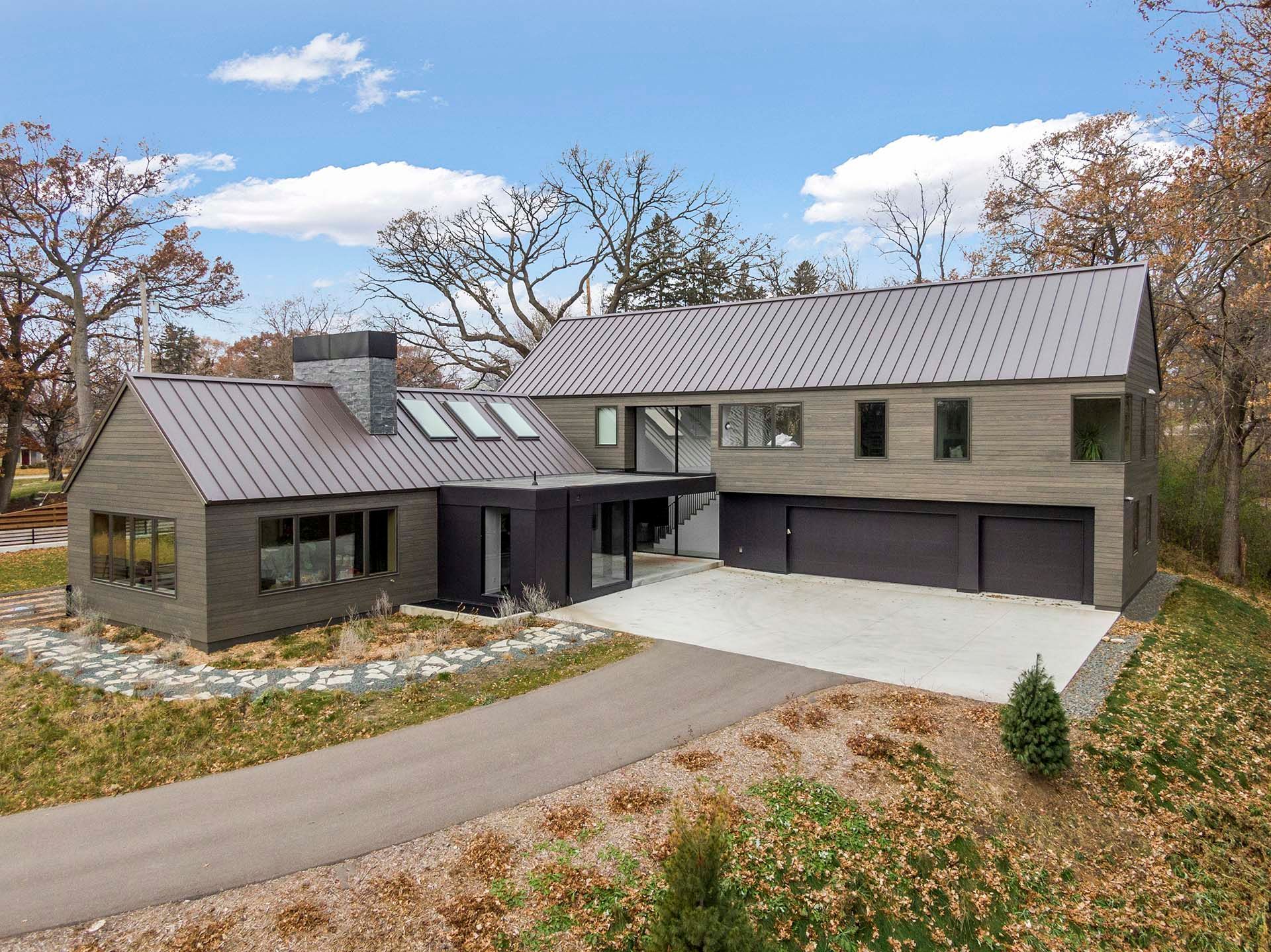 An aerial view of a large house with a metal roof surrounded by trees.