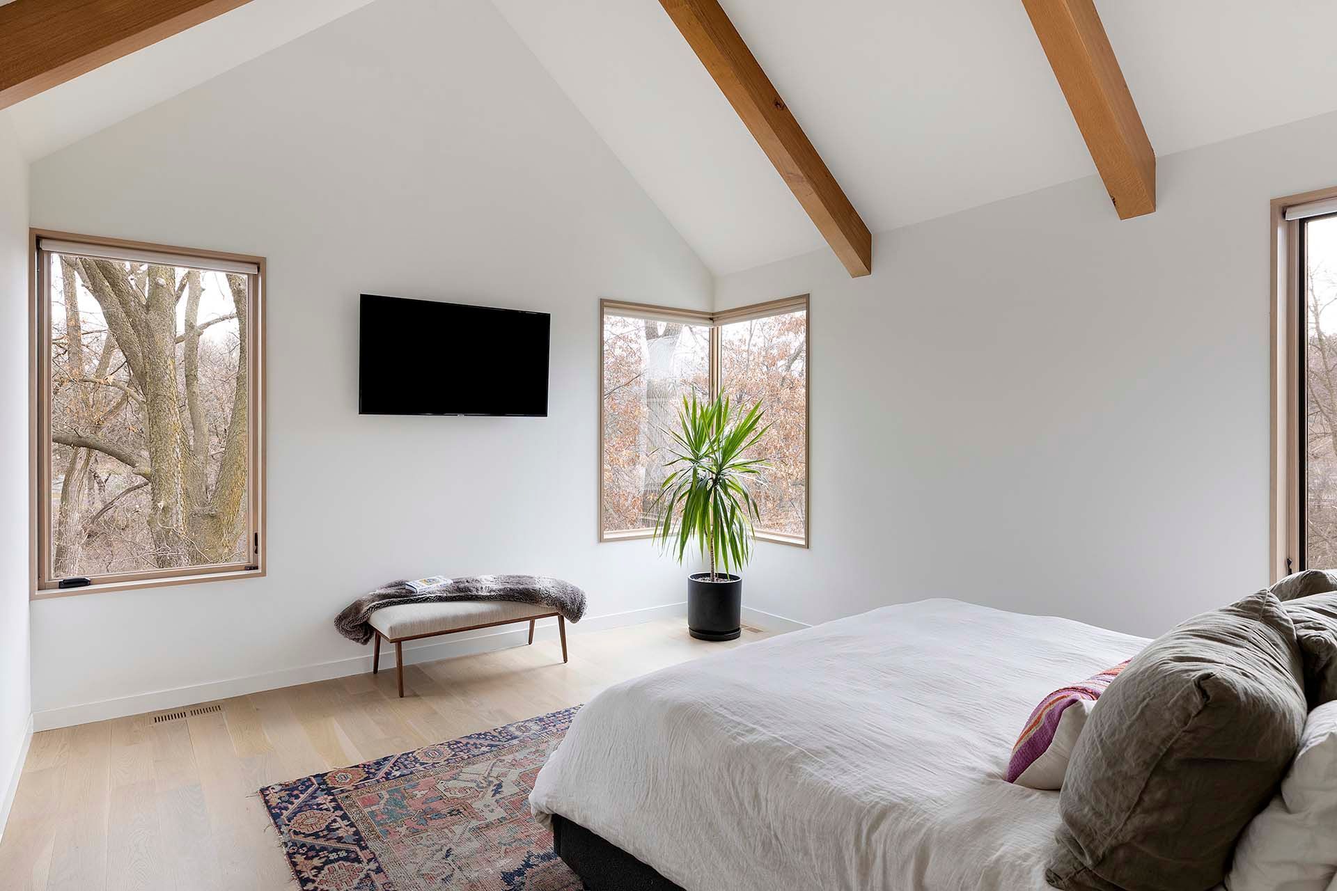 A bedroom with a large bed and a flat screen tv on the wall.