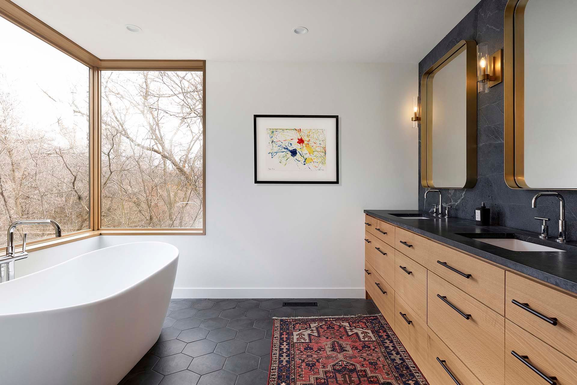 A bathroom with a tub , sink , mirror and window.