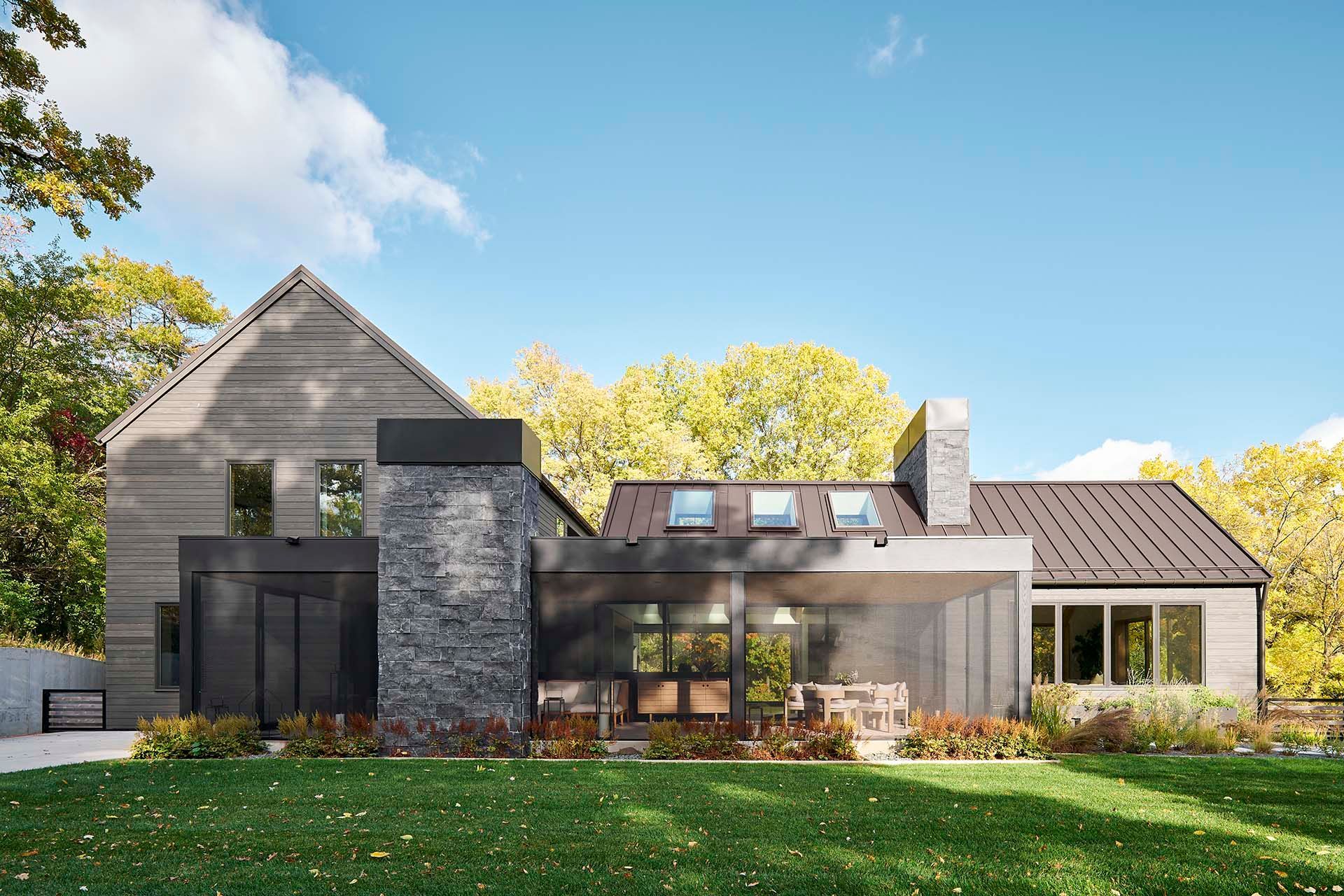 A large house with a lot of windows is sitting on top of a lush green lawn.