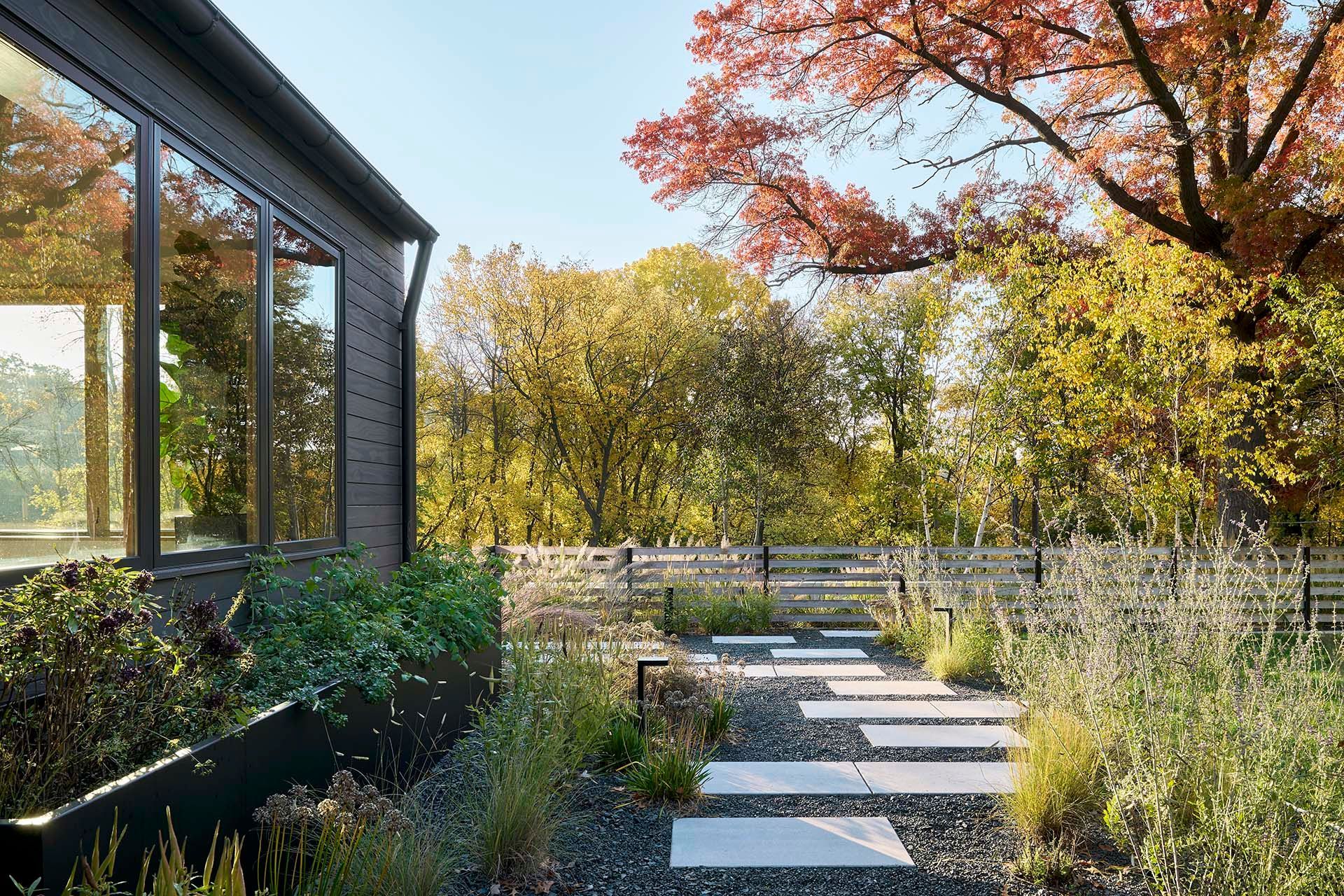 A walkway leading to a house surrounded by trees and bushes.