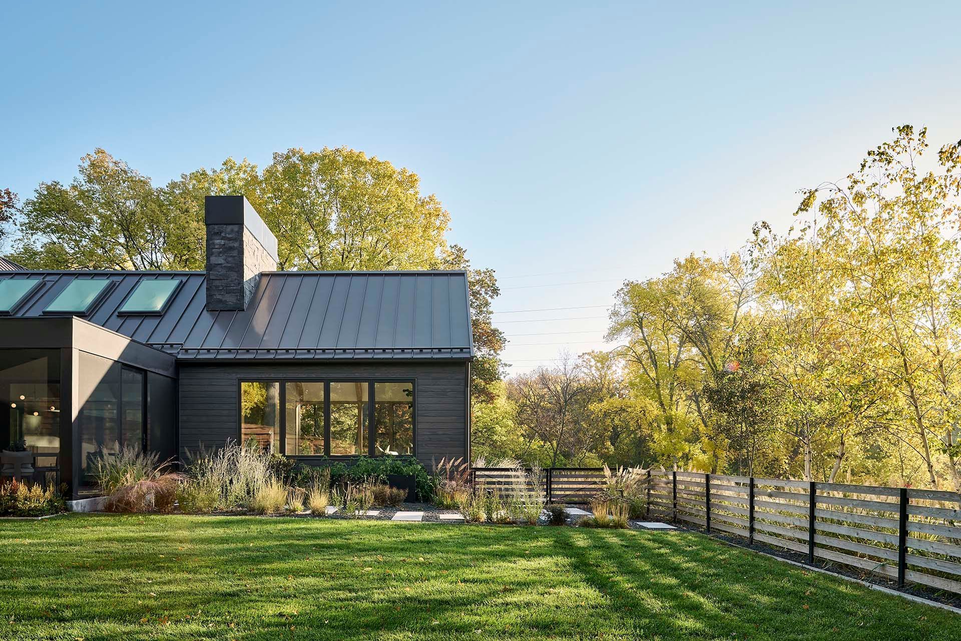 A black house with a large lawn in front of it.