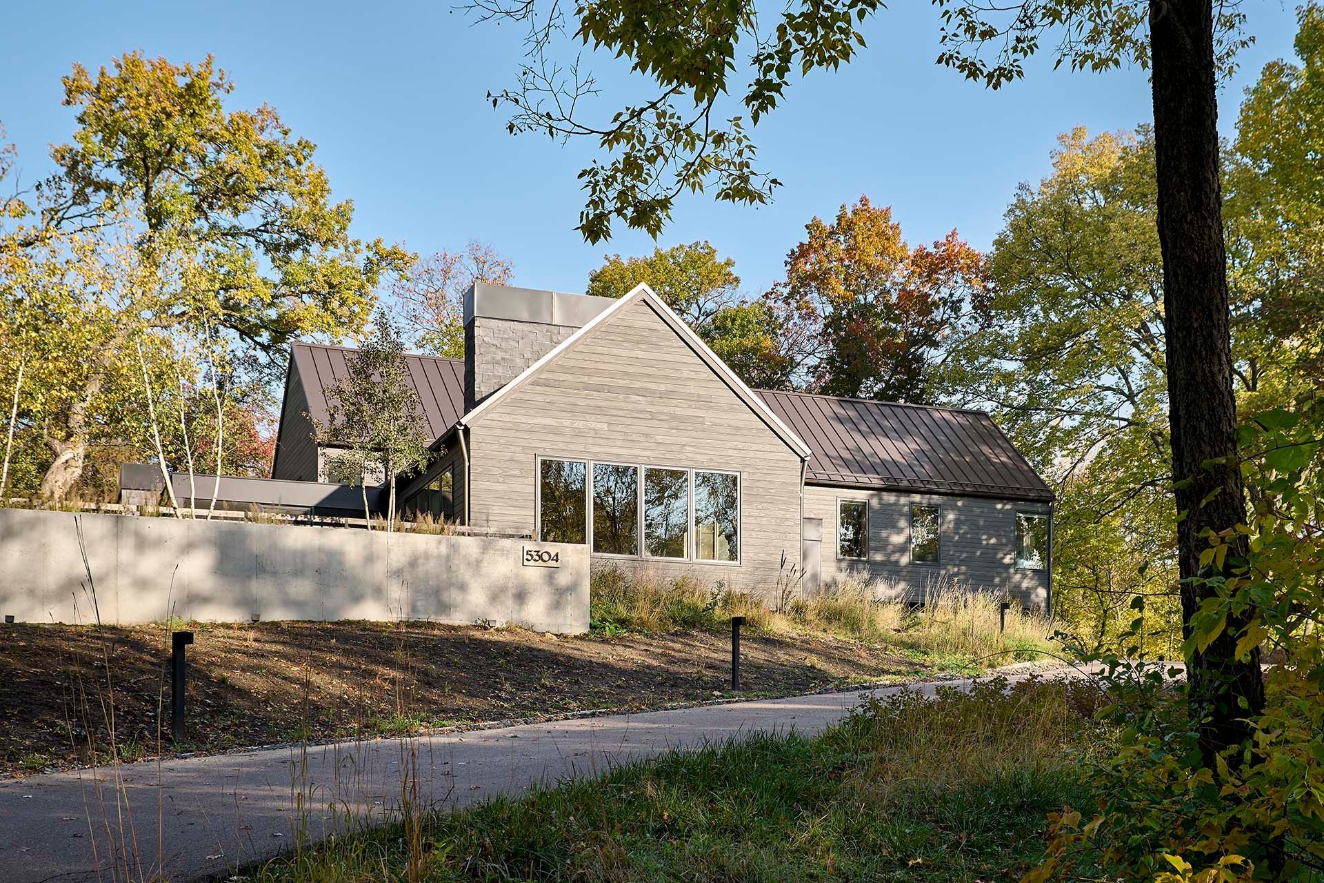 A house with a lot of windows is surrounded by trees.